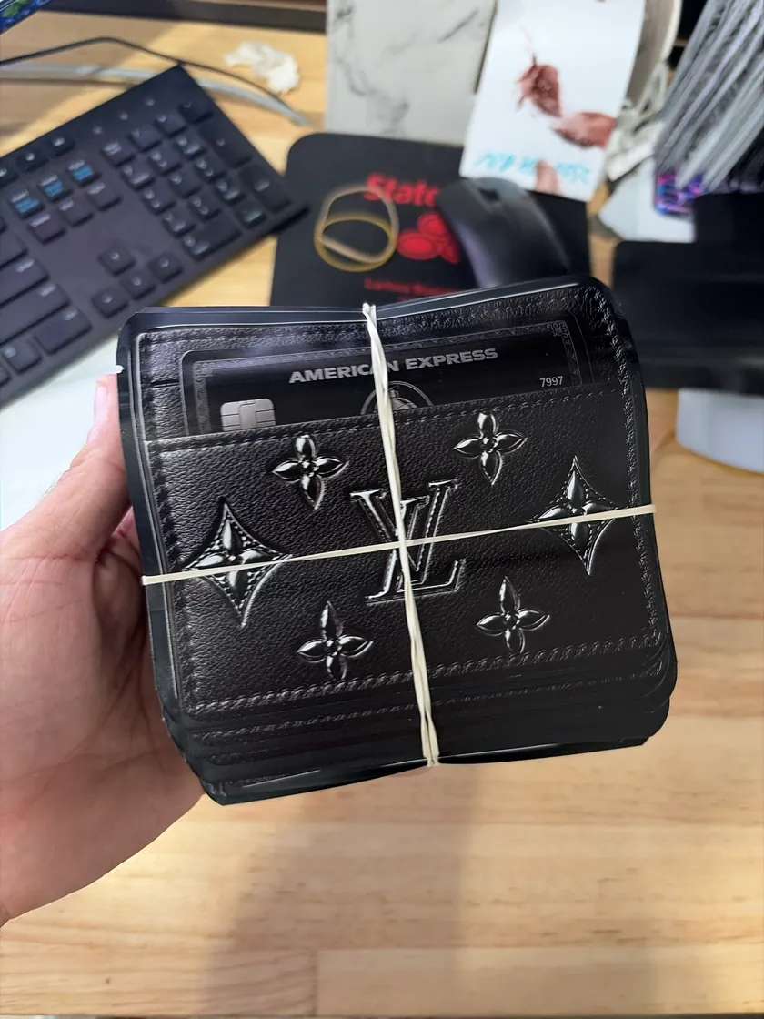 Hand holding a stack of black wallet shaped printed bags
